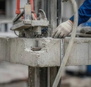 Công nhân đang sử dụng máy cắt kim cương hiện đại để thực hiện kỹ thuật cắt hạ sàn bê tông chính xác tại công trình xây dựng.